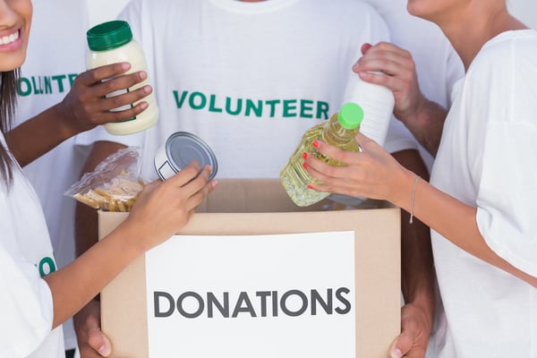 Group of volunteers putting food in donation box